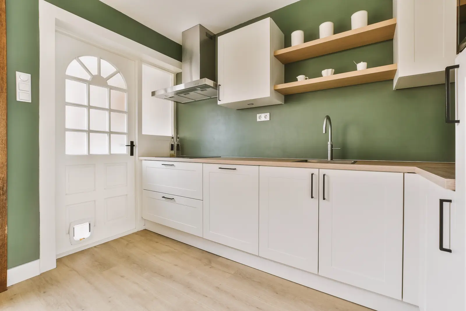 White shaker kitchen cabinets against a green wall