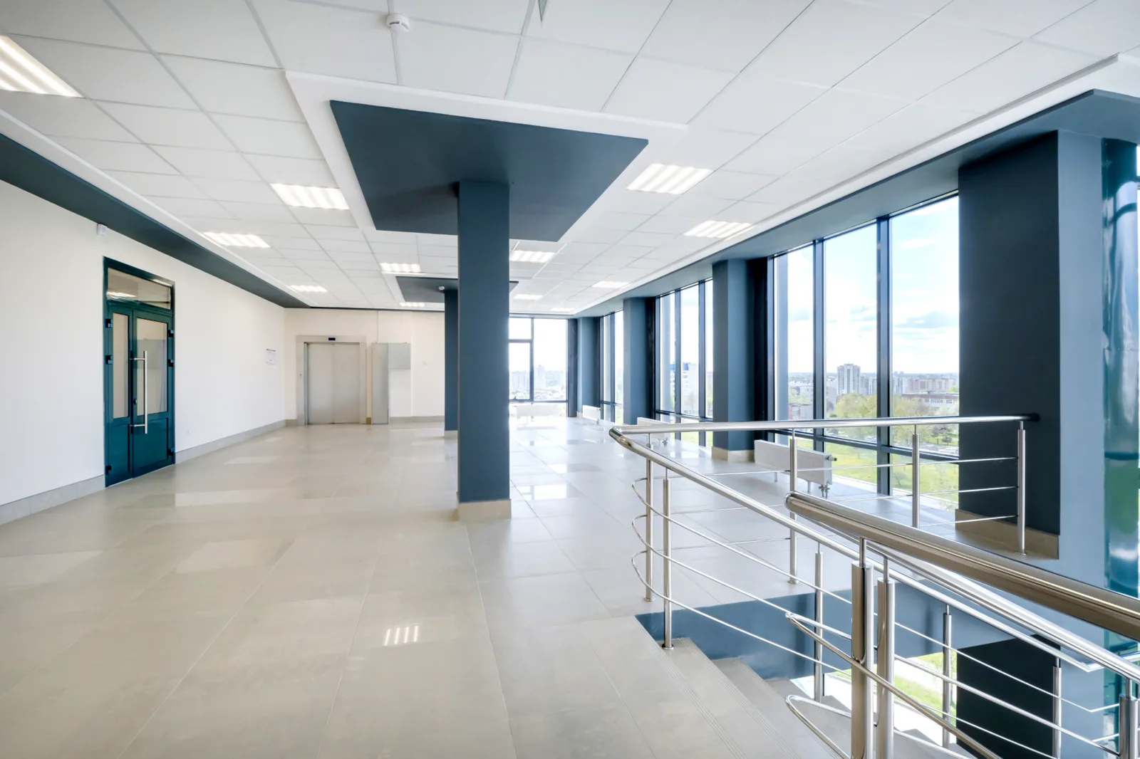 Bright commercial lobby with slate blue painted columns and soffits, white walls and floor-to-ceiling windows