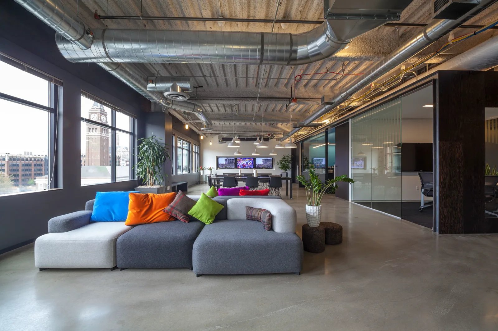 Loft office with charcoal painted walls, exposed ductwork and a lounge area by the windows