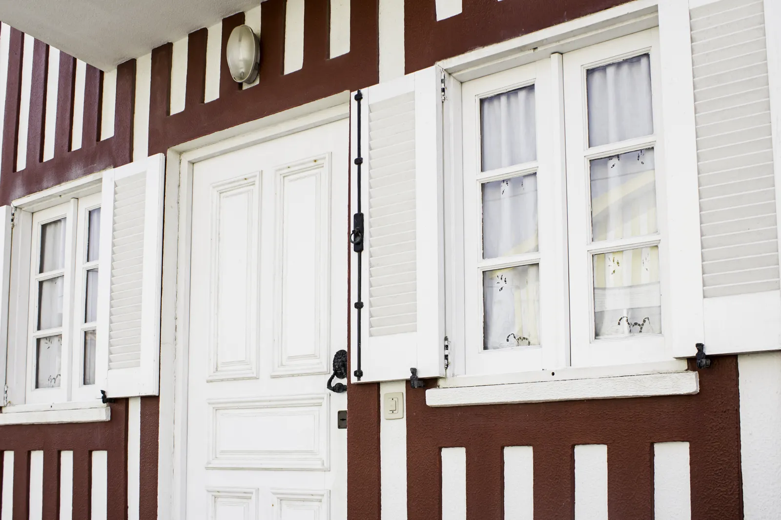White painted front door and shutters on a house with dark brown trim