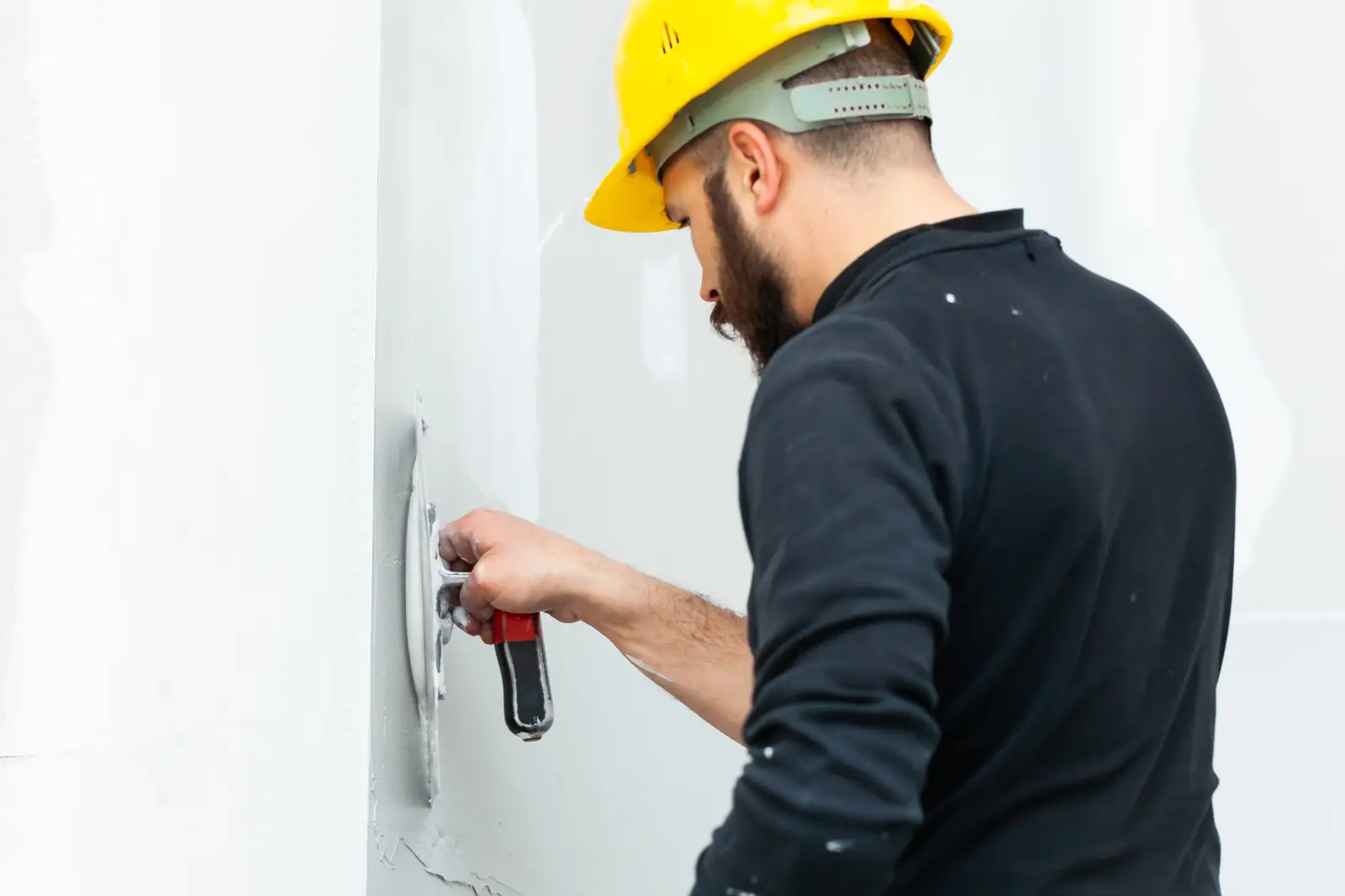 Worker smoothing joint compound on a wall with a trowel