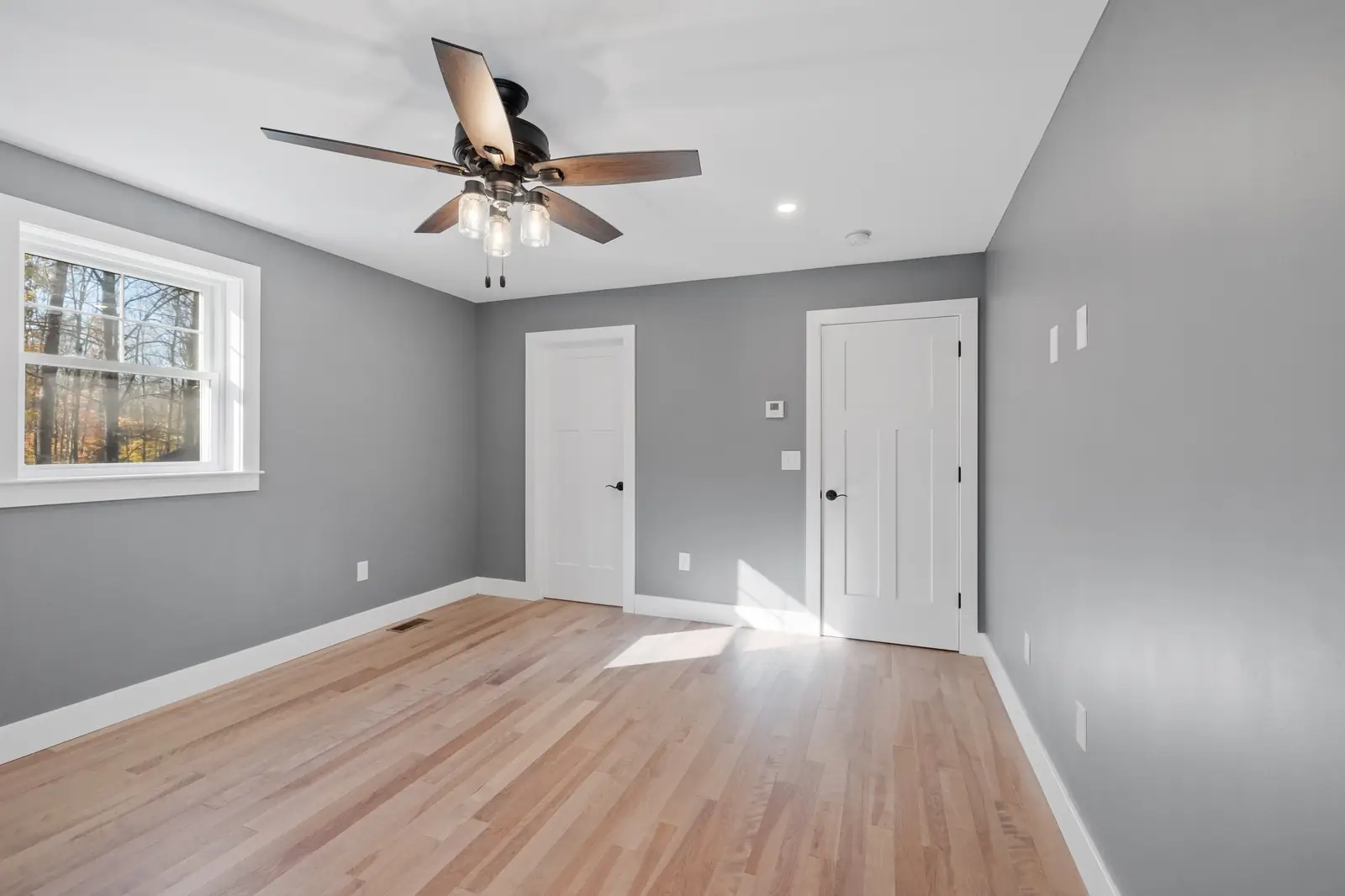 Empty bedroom with gray walls, white doors and white baseboards