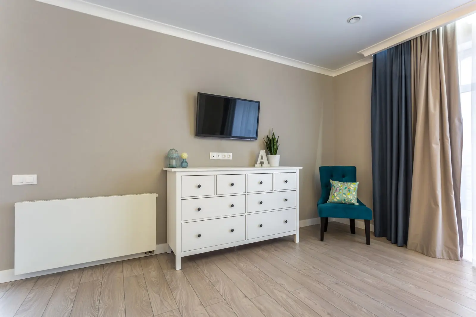 Bedroom with greige painted walls, white crown molding and white baseboards