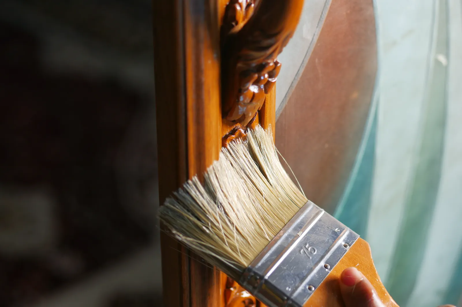 Brush applying finish to a carved wooden frame
